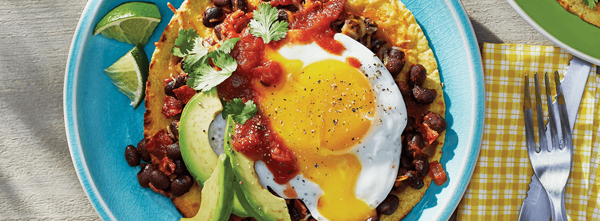 <p>huevos rancheros on blue plate with fork to the side</p>