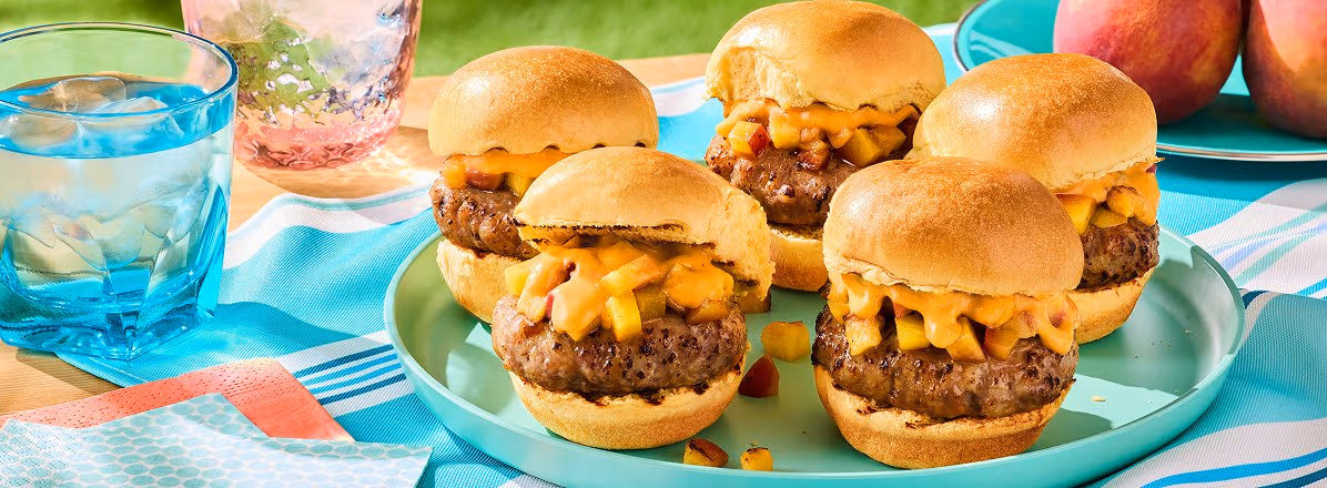 platter of BBQ Sausage Sliders with peach salsa and Compliments Crema Sauce Chili Lime on a picnic blanket outside