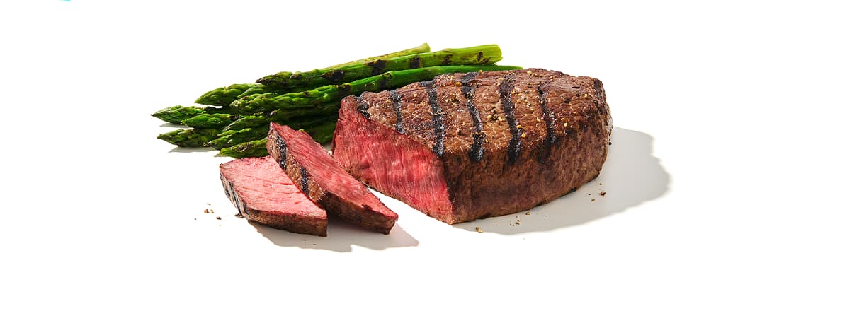 Sirloin Tri Tip Grilling steak on a plate with side of grilled asparagus and mushrooms to the side
