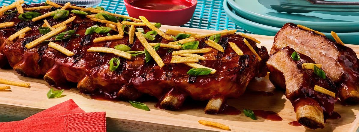 Maple glazed ribs on cutting board topped with Hickory sticks and slices green onions