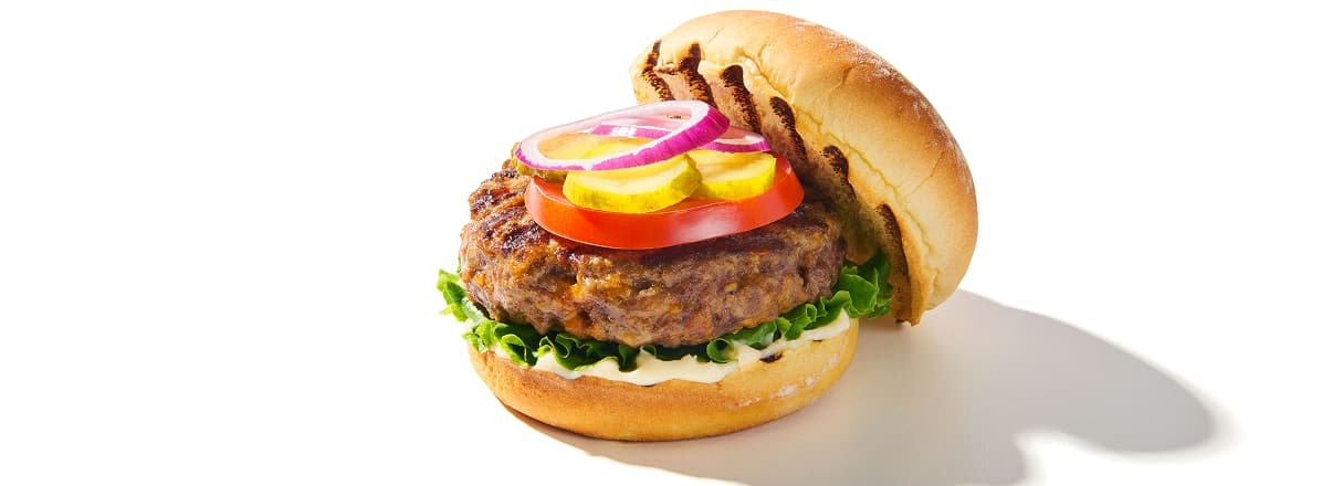 Bacon & Cheddar burger topped with lettuce, tomato, and pickles on a bun.