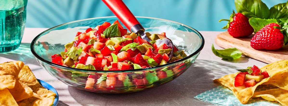 side profile of clear bowl with fresh Strawberry Salsa with Avocado, Lemon and Basil, and side of tortilla chips