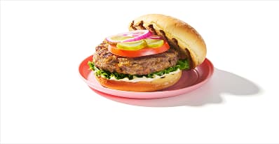 Open-face burger, dressed with mayo, lettuce, tomato, pickle and red onion.