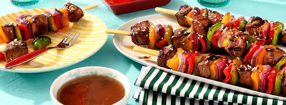 Maple-Ginger Beef Kabobs on a large serving platter and smaller side plate with extra glaze in small white bowl