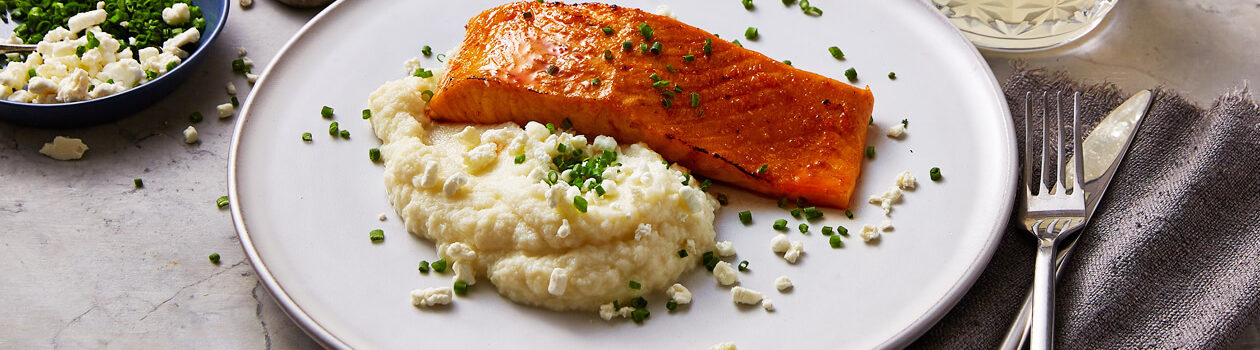 cauliflower puree with a side of cooked salmon and topped with fresh chives