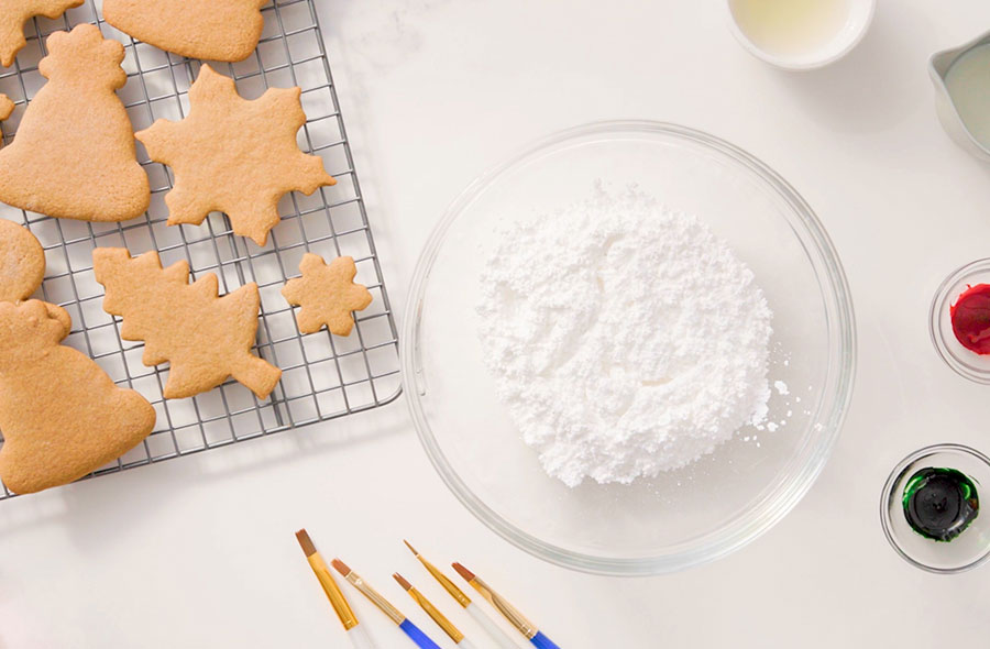 cookies, icing sugar, milk and food colouring on a table