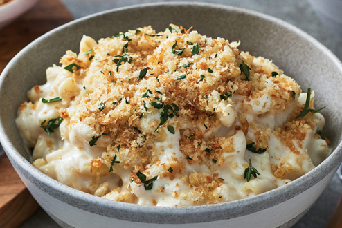 Creamy mac â€™nâ€™ cheese with crispy topping in white and grey Bowl.