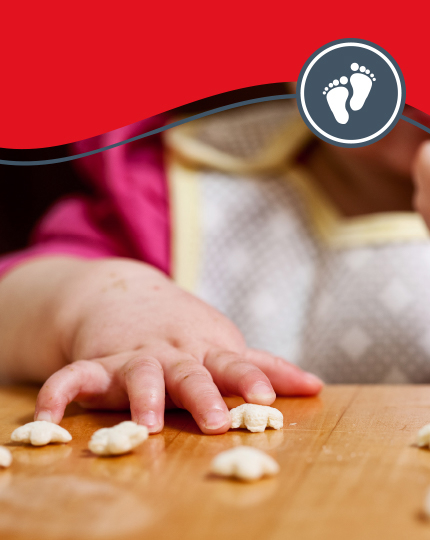 Fingers of a toddler trying first finger foods