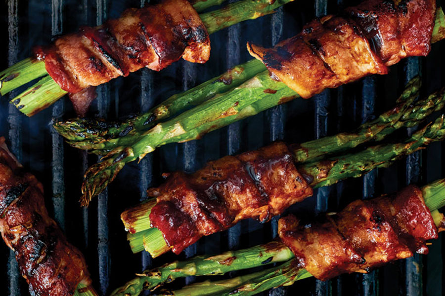 bacon-wrapped asparagus on a grill.