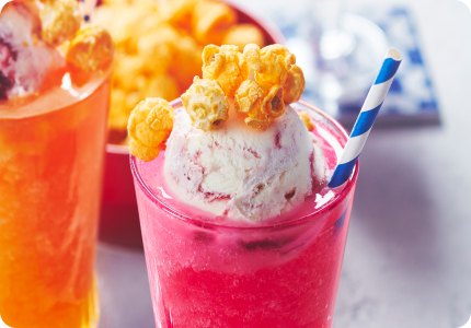 Pink and orange sparkling slushie snack floats in parfait glasses with colourful straws and frozen yogurt scoop on top