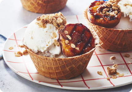 An assortment of fresh fruit desserts: individual peach crisp in a waffle cup, a fresh berry cheesecake parfait and red hot chili strawberries spooned over thick yogurt.