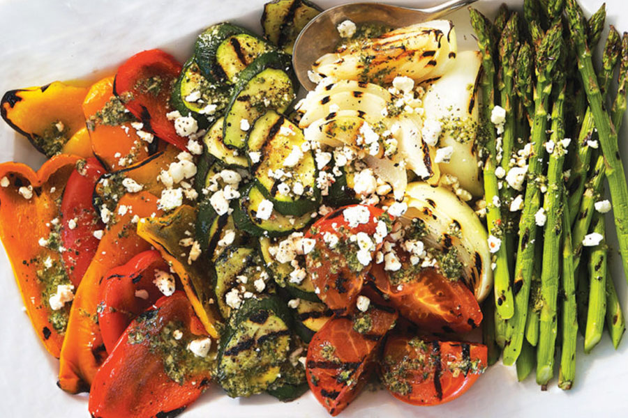A white platter of a grilled summer-vegetable medley, including peppers, asparagus, onions, and zucchini.