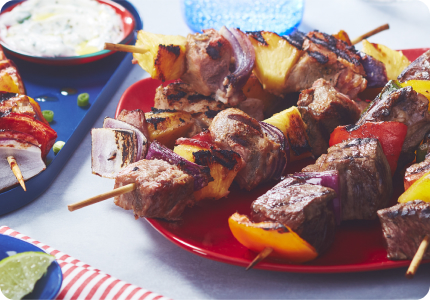 Table with three platters of barbecue skewers and meat kabobs inspired by world flavours