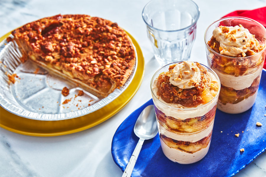 Two breakfast parfaits on a blue serving dish with a half gone apple pie