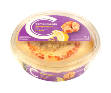 Clear container of Compliments Roasted Garlic-Topped Hummus with purple label