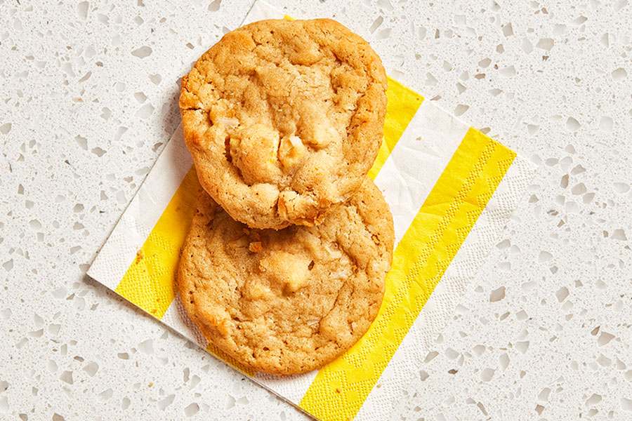 Two piña colada cookies sitting atop a yellow and white–striped paper napkin.