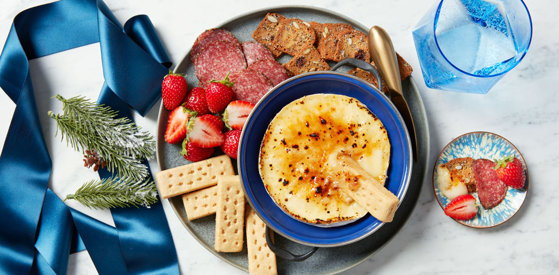 Fruit, cured meat, crackers and shortbread arranged on a plate around a bowl of Double Cream Brie Brûlée.