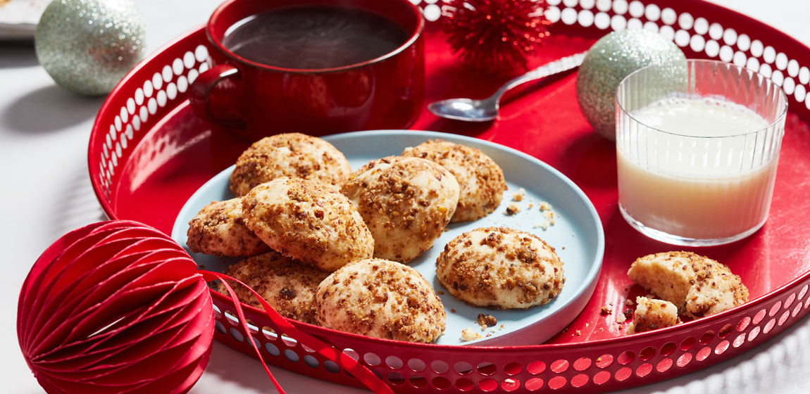 white marble tabletop with a red serving tray and white plate of roasted chestnut shortbread cookies.