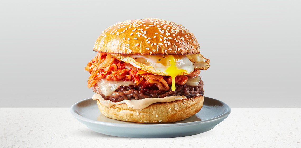 Kimchi Burger: sesame bun, Compliments Angus Beef & Smoked Pork Belly Burger, fried egg, kimchi, cheese slice, and Kimchi Mayo.