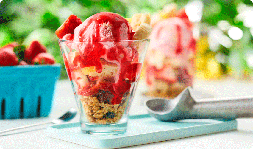 parfait glass of strawberry shortcake sundae with strawberry-flavoured syrup, granola and crumbled lemon cookies