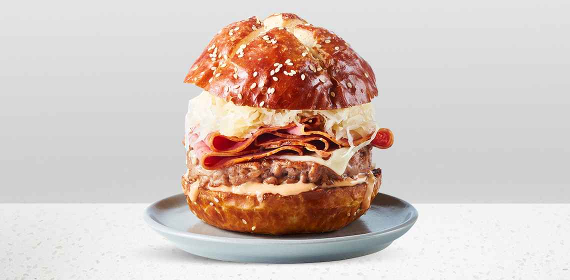 The Reuben Burgerâ€‹â€‹: pretzel or dark seeded bun, Compliments Prime Rib Beef Burger, sauerkraut, Thousand Island dressing, Swiss cheese, and Beef pastrami slices.