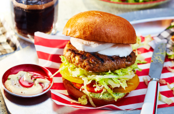 mild italian sausage burger with mozzarella, lettuce, tomato on a burger bun.