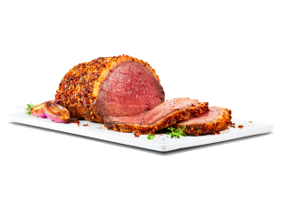 Fully roasted Sterling Silver beef Roast Royale with a few slices cut on a white cutting board, garnished with roasted shallots on the side