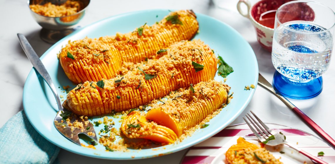 Aqua blue serving platter with three halves of roasted butternut squash, cut in hasselback-style and topped with sage and breadcrumbs