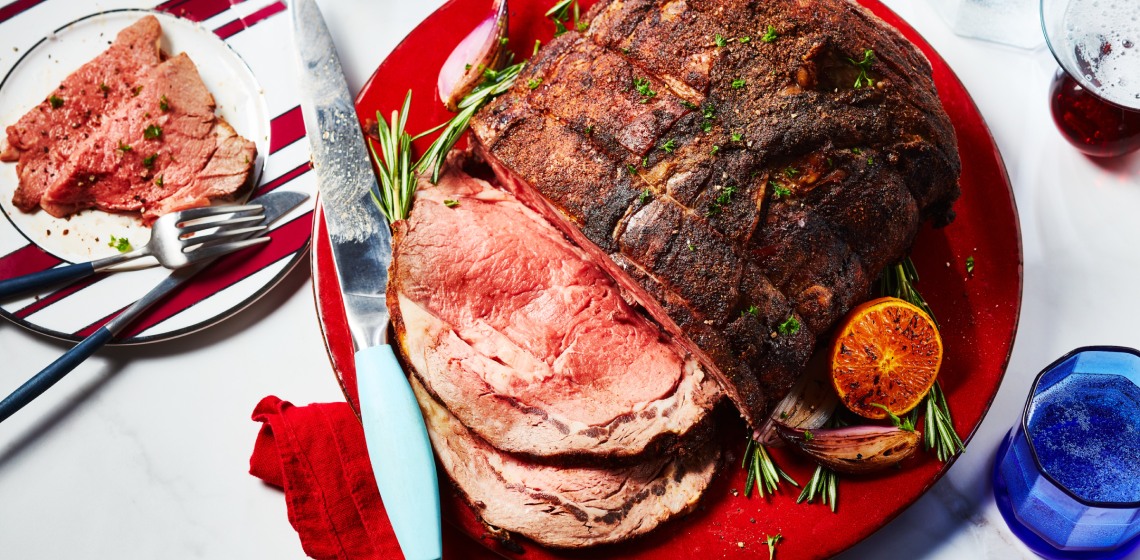round red serving platter with moroccan-spiced roast beef, with slices cut on one end, and a rosemary and citrus garnish on the side