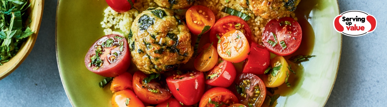 Bowl of turkey and spinach meatballs with sliced grape tomatoes and couscous